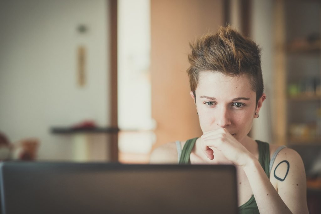 Online Therapist for LGBTQ+ in Austin, Texas young LGBTQ adult in Texas looks at computer screen during online therapy session