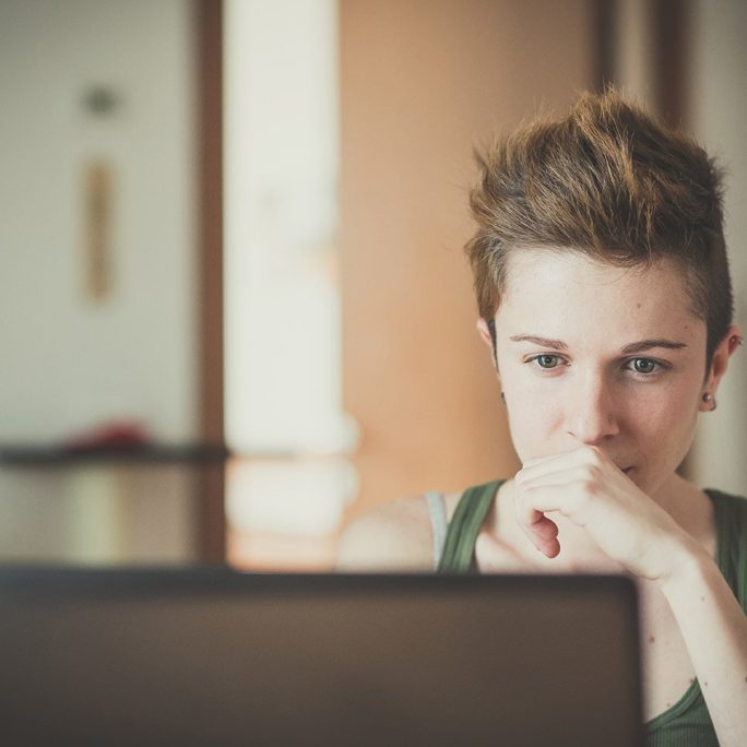 young LGBTQ adult in Texas looks at computer screen during online therapy session