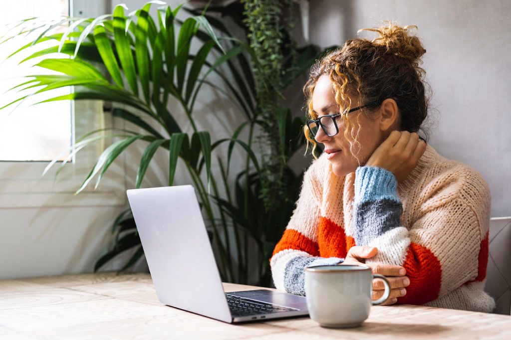 A Gen Z woman sits with a cup of tea during her online therapy session in San Antonio, Texas