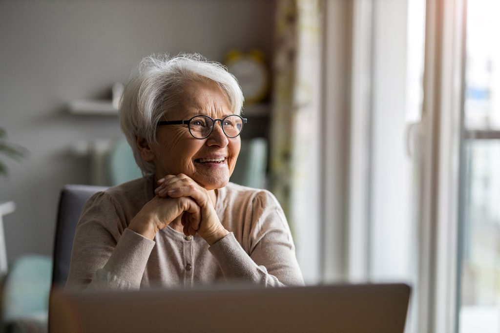 Online Therapist for Seniors in Texas Takes Medicare A senior-aged woman in Texas smiles as if she is laughing while looking away from the computer during an online therapy session